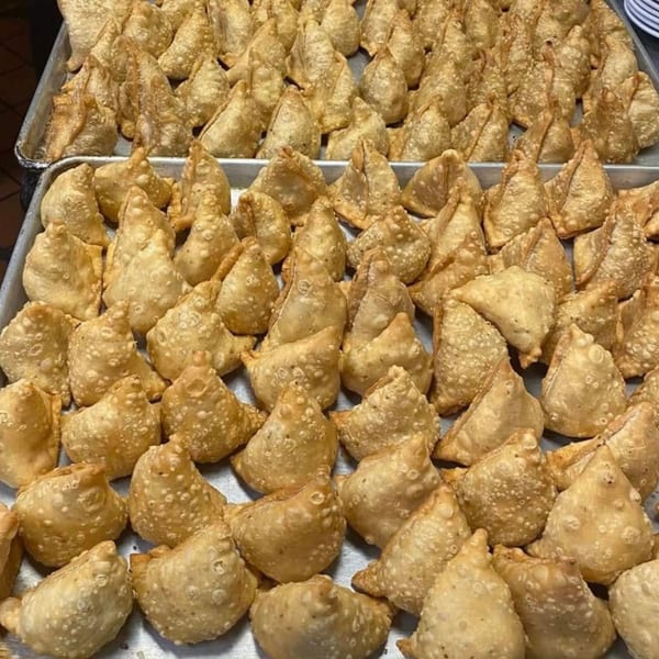 Two large trays overflowing with golden-brown, crispy Indian samosas, ready to be served.